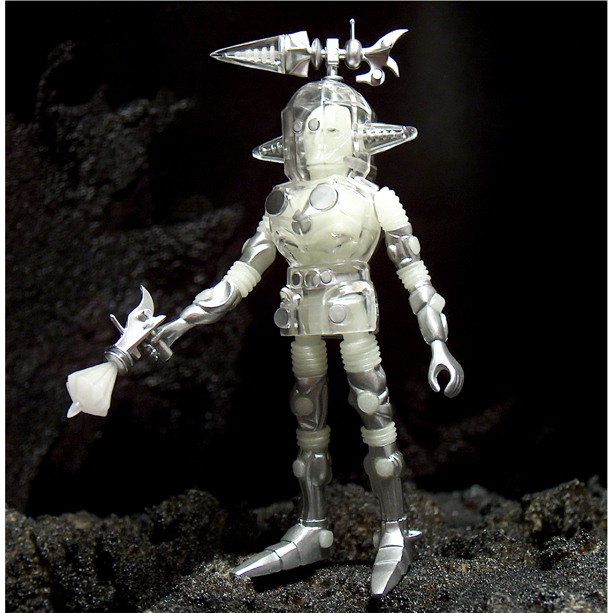 A silver GAMMA X COSMIC RADIATION action figure holding a sword on a rock.