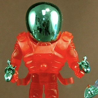 A red and green 2012 HOLIDAY CYCLOPS WITH GREEN ACC'S FACTORY BAG action figure with a green helmet.